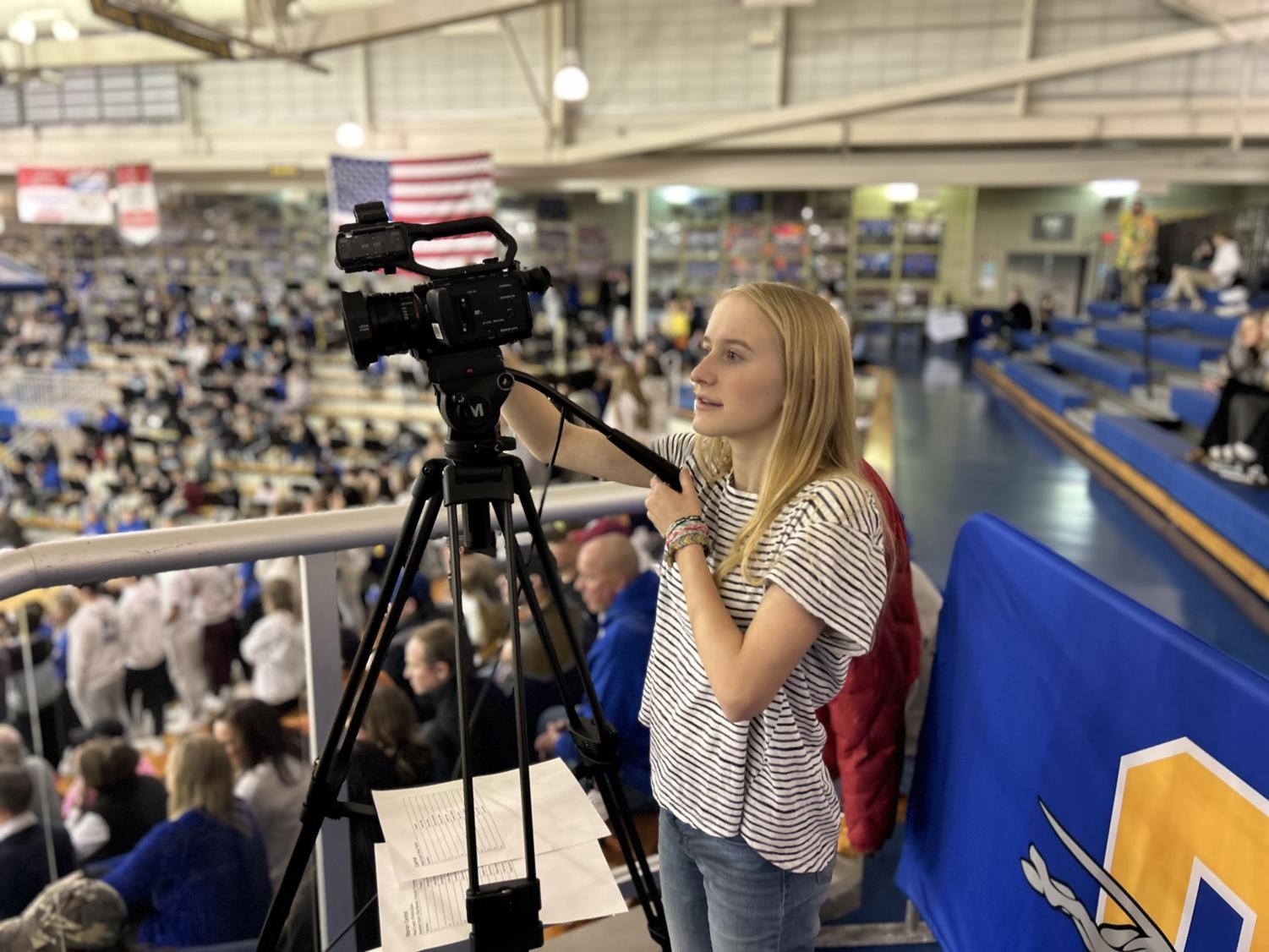 Kate operating a camera at a basketball game