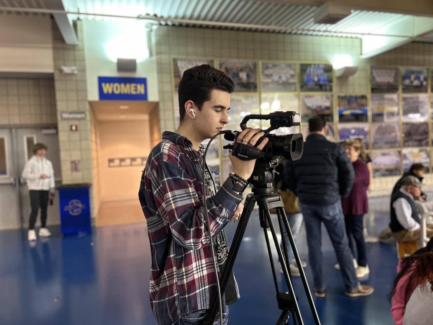 Cole operating a camera at a basketball game