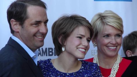 A man and two women looking at a camera and smiling at a red carpet premiere