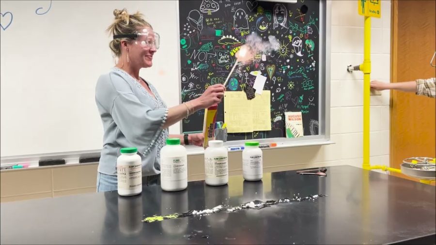 A science teacher wearing safety goggles doing a science experiment with fire