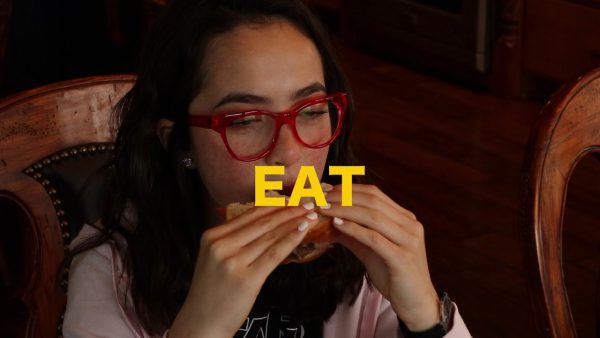 Maya eating a sandwich with the text, Eat in front of her