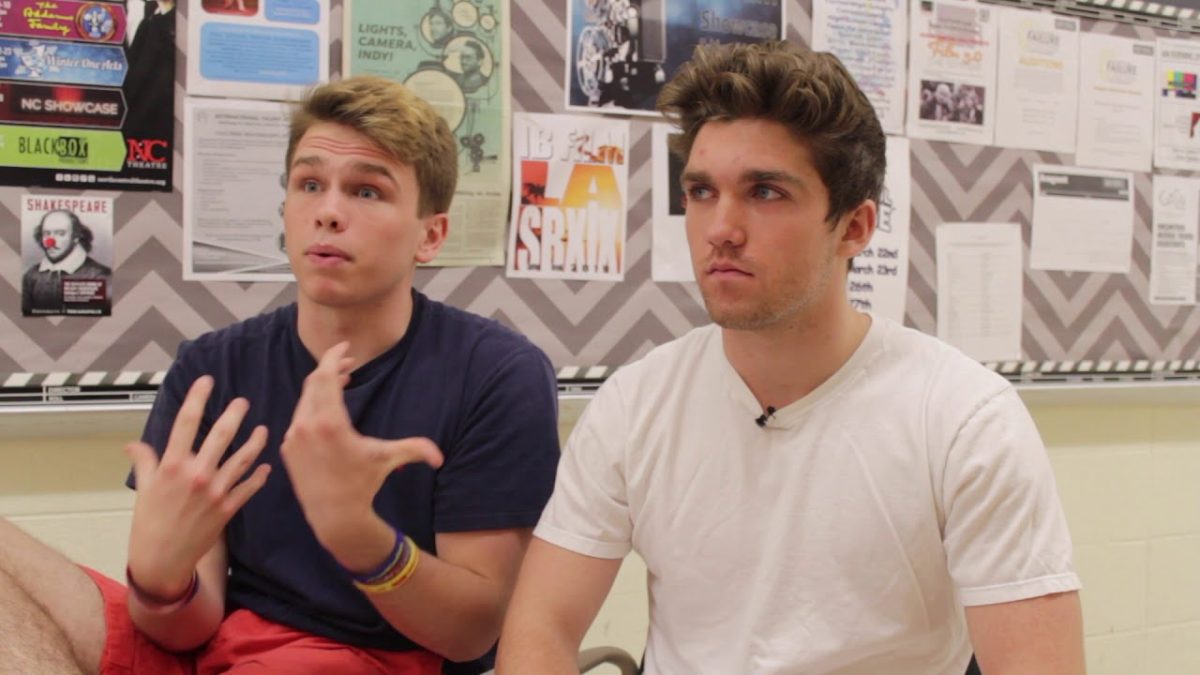 Brian Deheer and Stefan Buba sitting in front of a bulletin board full of papers