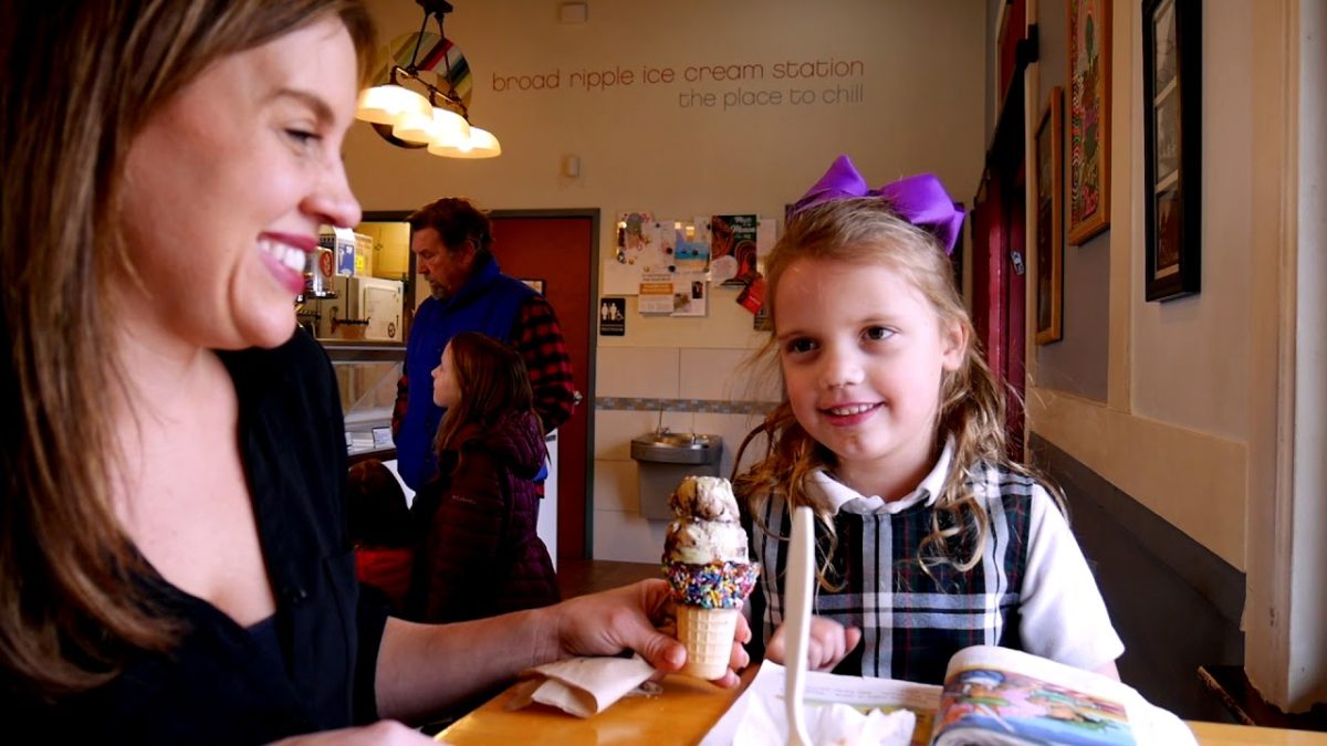 A mother and daughter holding an ice cream cone in an ice cream shop